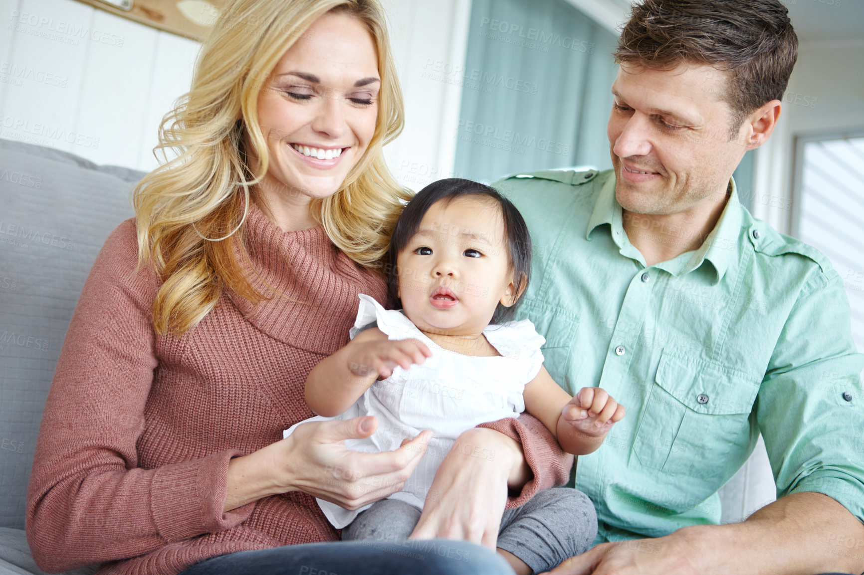 Buy stock photo Love, happy family and adopted baby in home for care, support or bonding together. Mother, father and cute foster kid with parents for connection, interracial or diversity with toddler in living room