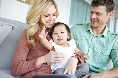 Buy stock photo Care, happy family and adopted baby in home for love, support or bonding together. Mother, father and cute foster kid with parents for connection, interracial and diversity with child in living room