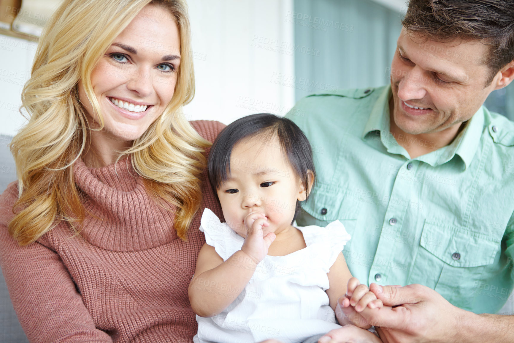 Buy stock photo Portrait, happy family and parents with adopted baby in home for love, support or bonding together. Mother, father and face of cute foster kid with people for interracial connection or play in lounge