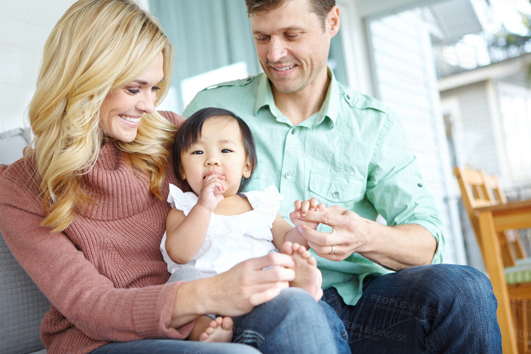 Buy stock photo Adoption, happy family and parents with baby in home for love, support or bonding together. Mother, father and cute foster kid with people for interracial connection, care and playing with orphan