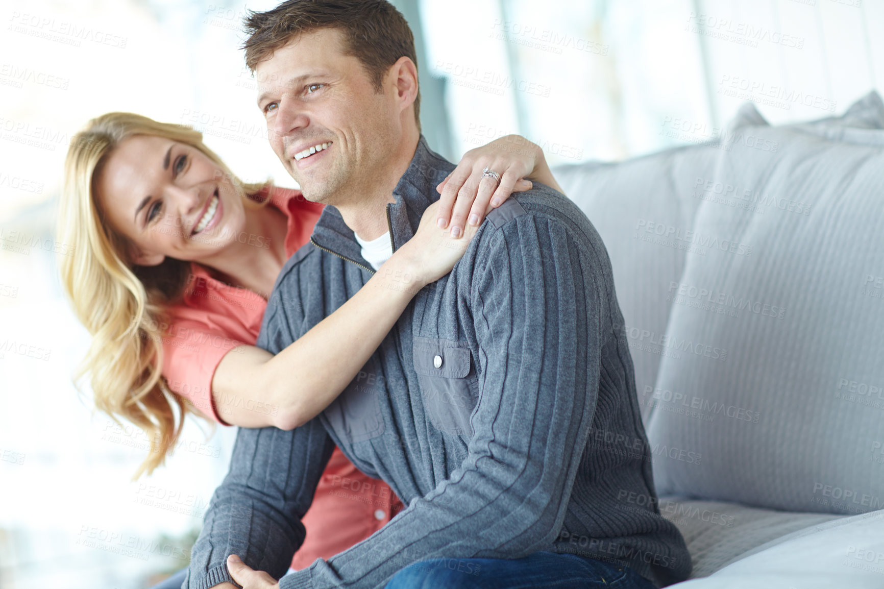 Buy stock photo Love, hug and happy couple in home for relax, loyalty and bonding together in lounge. Smile, man and woman embrace on sofa for support, connection and care for relationship commitment with partner