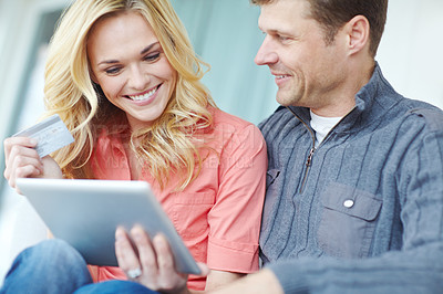 Buy stock photo Cropped shot of a happy mature couple shopping online using a digital tablet while relaxing together at home