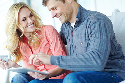 Buy stock photo Cropped shot of a happy mature couple shopping online using a digital tablet while relaxing together at home
