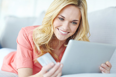 Buy stock photo Cropped shot of a beautiful young woman using her digital tablet and credit card to shop online