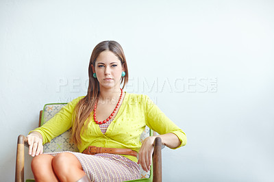 Buy stock photo A fashionable young woman sitting on a chair with copy space on the right. A lady in yellow top giving a pose while sitting on chair in landscape.  Happy middle-aged woman sits on chair with white back ground.