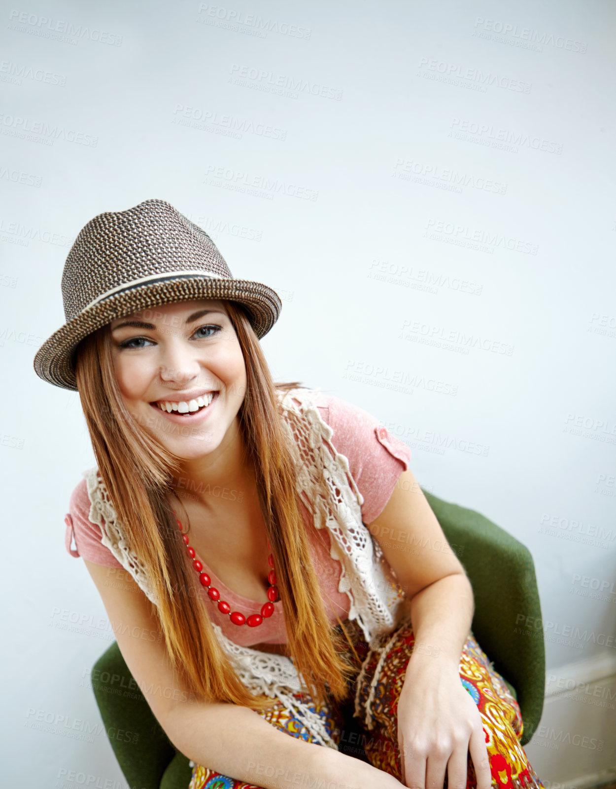 Buy stock photo Fashion, happy and portrait of woman in chair with vibrant, trippy and funky outfit for confidence. Smile, colorful and female designer from Portugal with vintage style by white wall in home or house