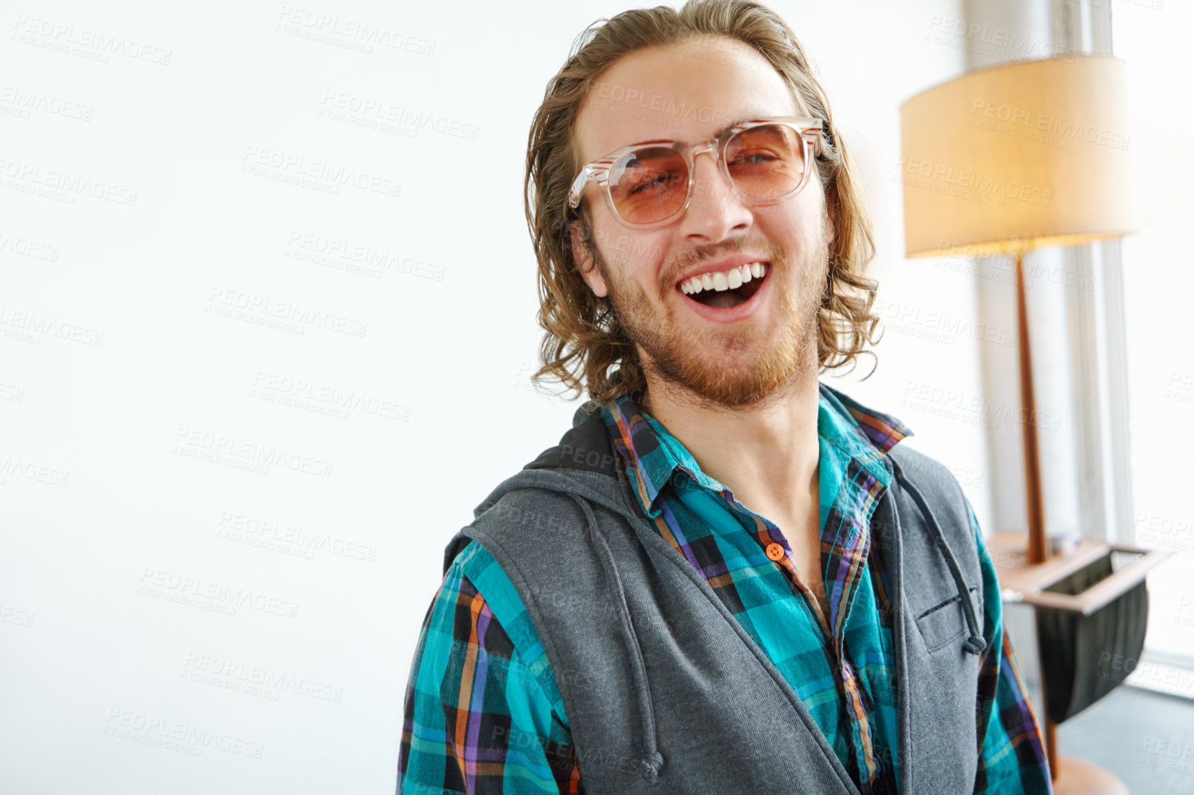 Buy stock photo A handsome young man in a trendy outfit laughing while standing in a home interior