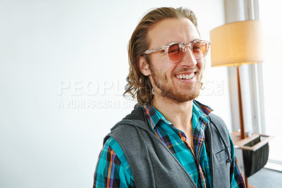 Buy stock photo A handsome young man in a trendy outfit laughing while standing in a home interior
