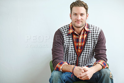 Buy stock photo A handsome young guy wearing a trendy outfit sitting with his hands clasped on an armchair indoors. A confident man sitting on chair with wearing trendy outfit giving a pose in white back ground in studio. 