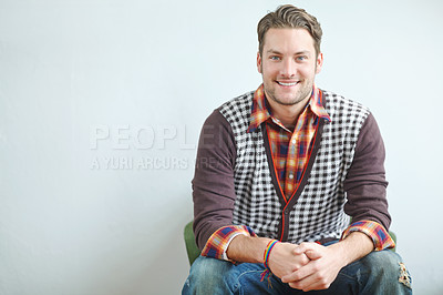 Buy stock photo A handsome young guy wearing a trendy outfit sitting on an armchair indoors