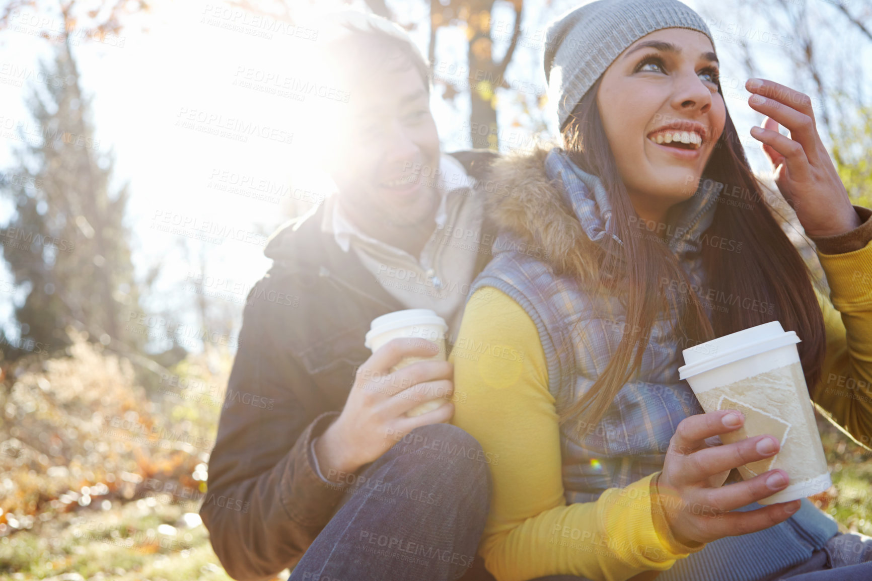 Buy stock photo Couple, laughing and relax with coffee in nature for bonding, funny joke and winter adventure with lens flare. People, happy and caffeine drink in forest on holiday, vacation or fun together in woods