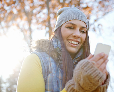 Buy stock photo Woman, smartphone and autumn outside or smile, reading and message on mobile app for communication. happy, internet and online or ecommerce, blog and social media in nature for connection or browsing