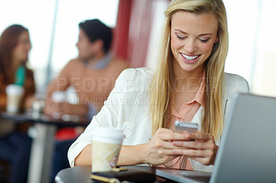 Buy stock photo A beautiful young woman using her smartphone in a busy coffeee shop
