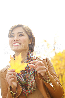 Buy stock photo Woman, autumn and happy with leaf in park with mockup, sustainability and thinking in nature. Korean person, thoughtful and daydreaming with plant foliage in outdoor environment with smile and relax