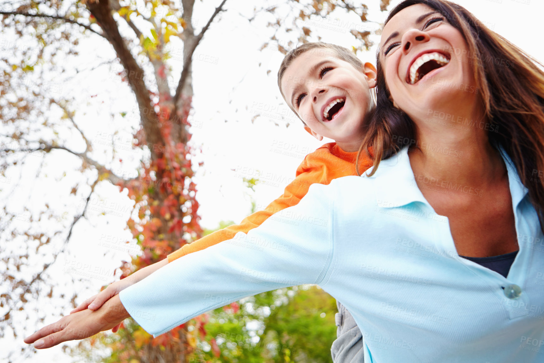 Buy stock photo Mother, son and outdoor with flying on piggyback for fun with bonding, support and care. Low angle, parent and happy or laugh with kid for child development, growth and childhood memories in England