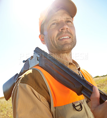 Buy stock photo A hunter standing in a field while holding his shotgun