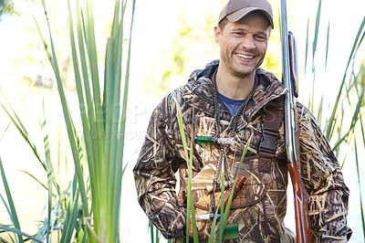 Buy stock photo A hunter wearing camo gear while holding his shotgun outdoors