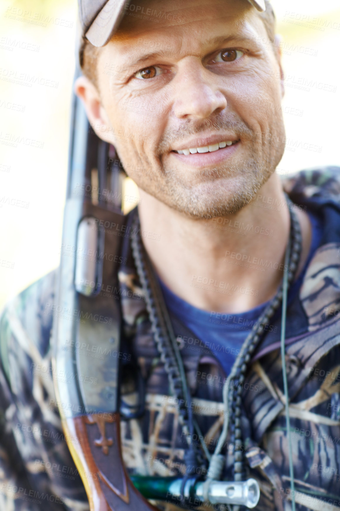 Buy stock photo A hunter wearing camo gear while holding his shotgun outdoors