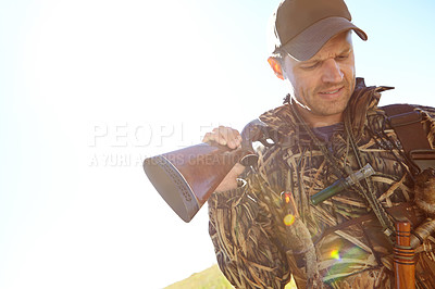 Buy stock photo A hunter wearing camo gear while holding his shotgun outdoors