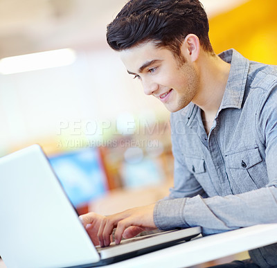 Buy stock photo Education, laptop and reading with student man in library on campus of college or university for development. Computer, smile and study with happy person at desk or table for research or typing