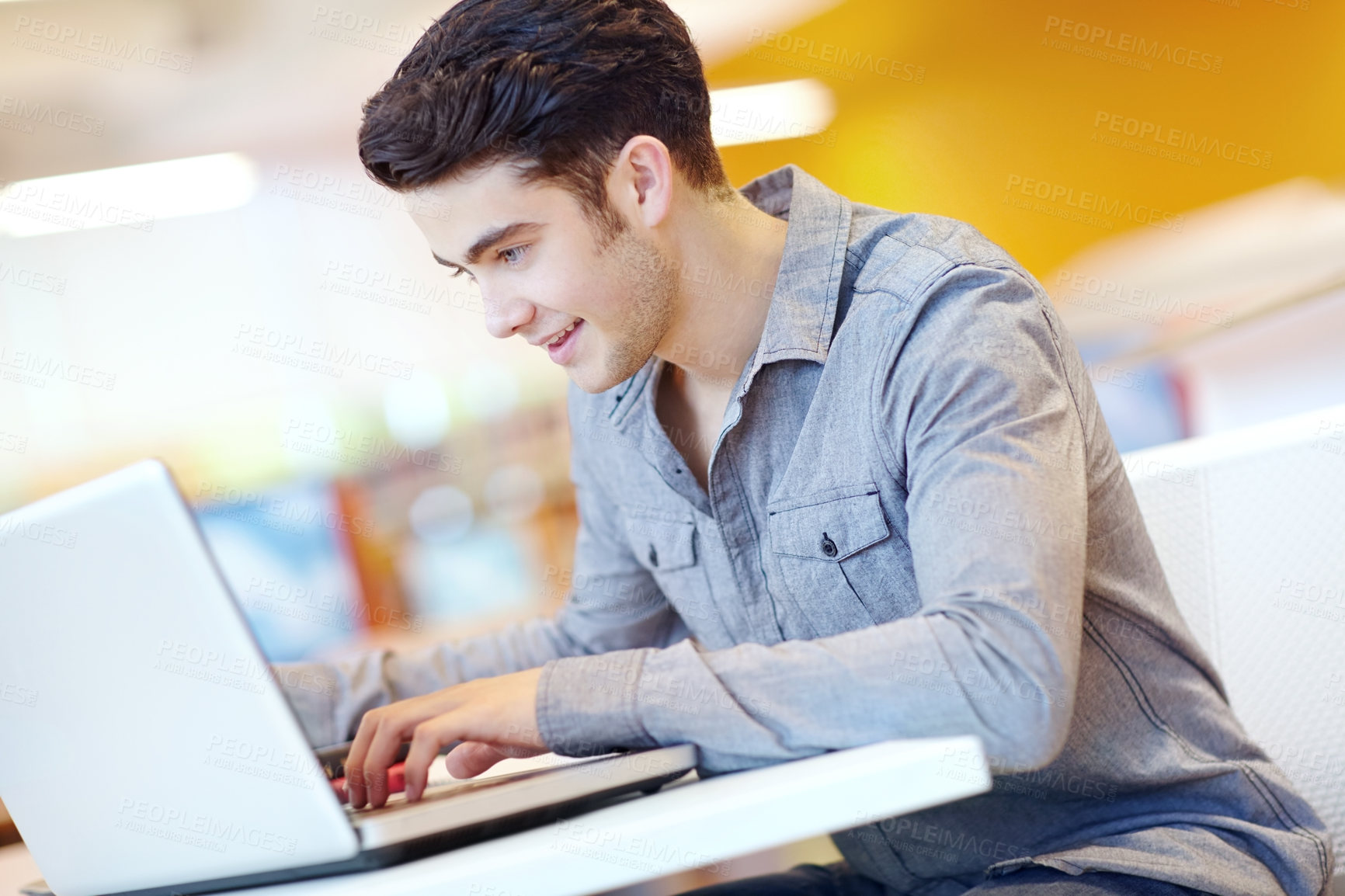 Buy stock photo Education, laptop and typing with student man in library on campus of college or university for development. Computer, learning and smile with happy person at desk or table for reading or research