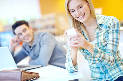 Buy stock photo Education, funny and phone with student woman in library on campus of college or university for development. App, smile and social media with happy person laughing at desk or table at school for meme