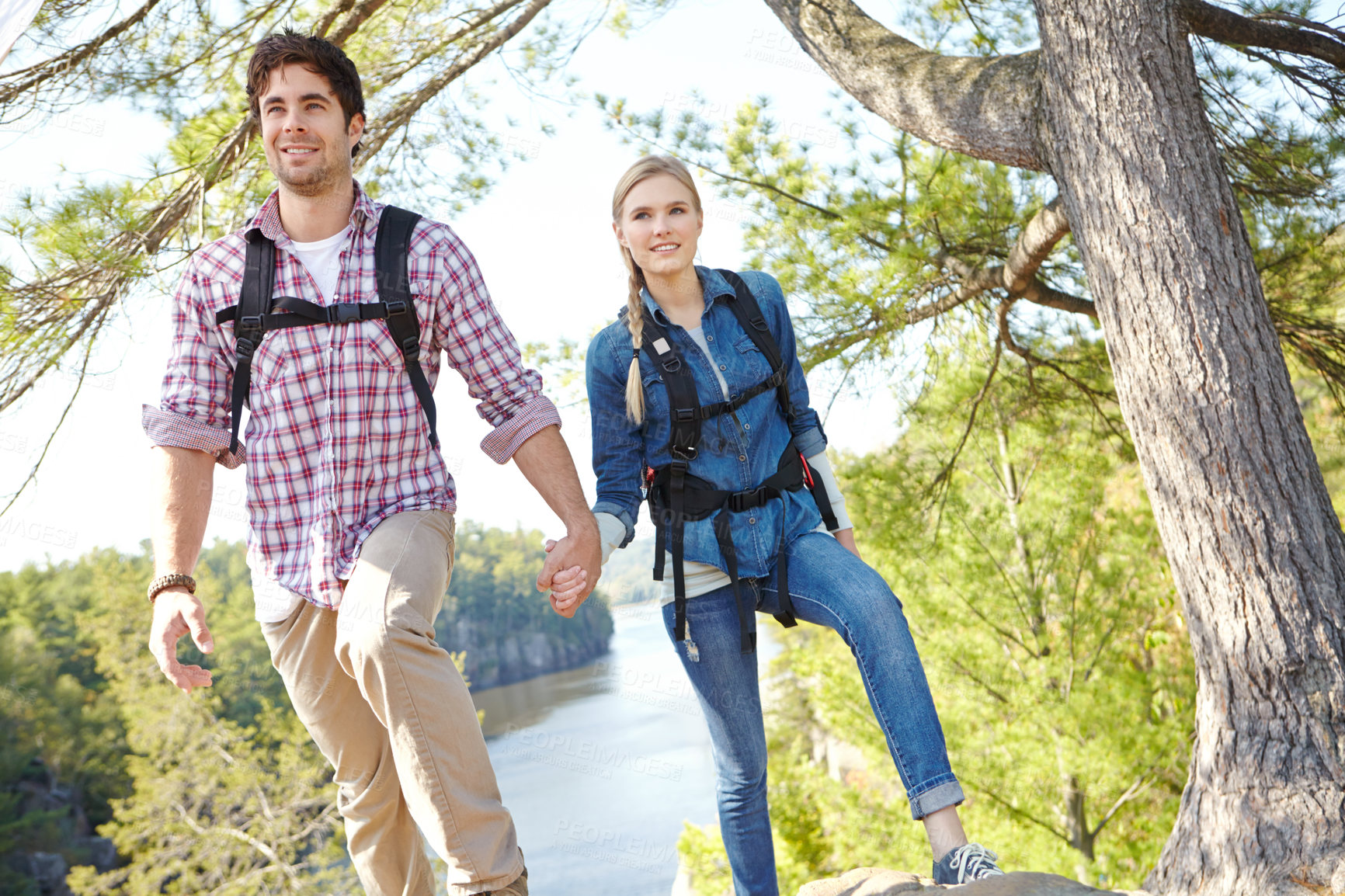 Buy stock photo Holding hands, nature or happy couple hiking by river for travel, outdoor adventure or journey. Mountain, woods or people in forest together on holiday vacation, lake trip or break to explore park