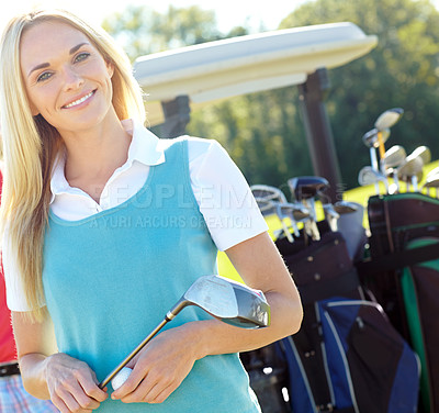 Buy stock photo Attractive smiling woman holding a golf club and golf ball standing infront of a golf cart
