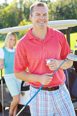 Buy stock photo Attractive smiling man holding a golf club and golf ball with an attractive woman and golf cart