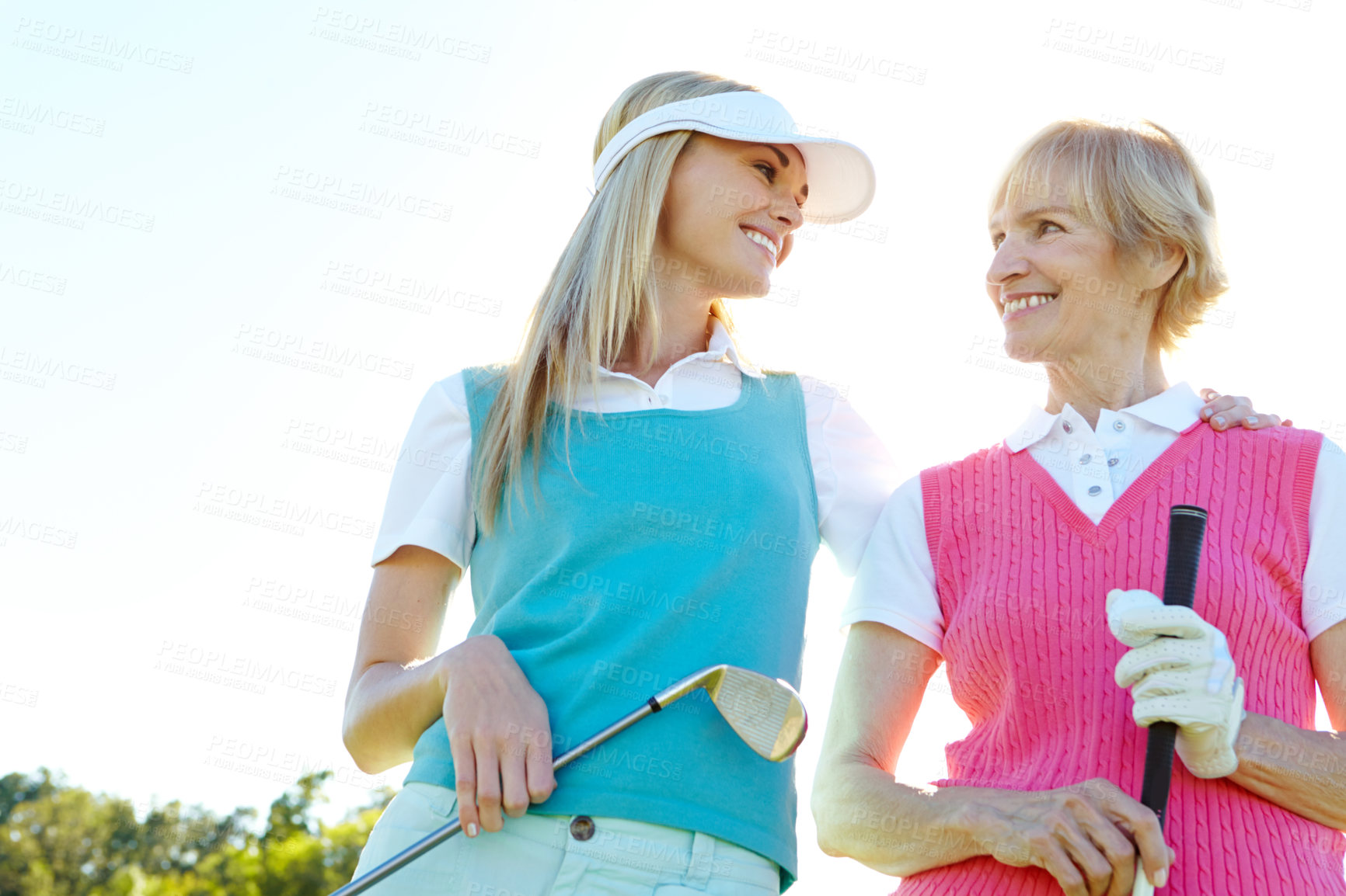 Buy stock photo Two attractive woman holding golf clubs and standing with their golf cart 