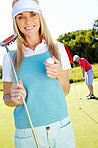 Smiling golfer with her putter and ball