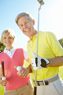 Buy stock photo Elderly couple holding their golf clubs and balls on the green
