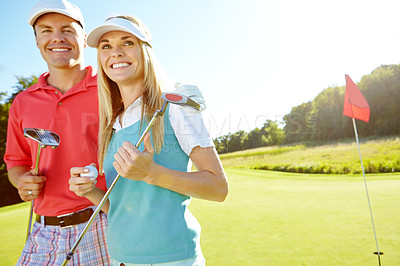 Buy stock photo Attractive young couple with their golf clubs and balls on the green