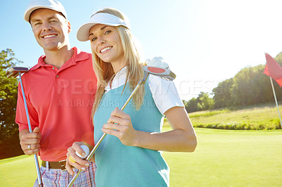 Buy stock photo Attractive young couple with their golf clubs and balls on the green