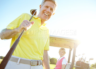 Buy stock photo Low angle shot of a handsome older golfer standing in front of a golf cart with his golfing buddy behind the wheel