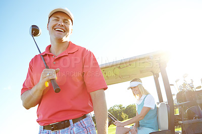 Buy stock photo Low angle shot of a handsome golfer standing infront of a golf cart with his golfing buddy behind the wheel