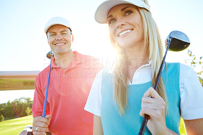 Buy stock photo Attractive couple with their golf clubs over their shoulders