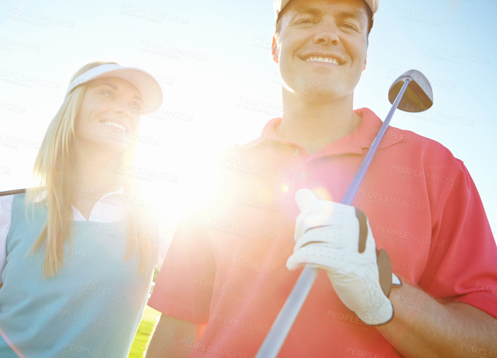 Buy stock photo Golf course, couple and smile for holiday, exercise or weekend hobby together on vacation. Lens flare, club and happy woman with man on green for competition, outdoor challenge and sports turf field