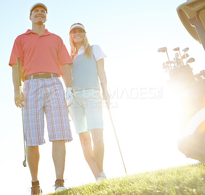 Buy stock photo Attractive golfing couple on the green with the sun setting behind them
