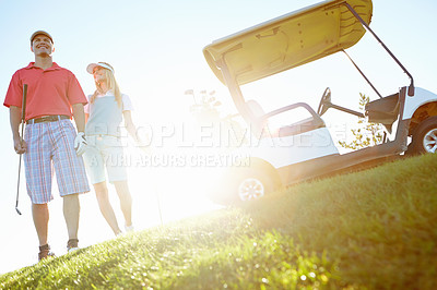 Buy stock photo Attractive golfing couple on the green with the sun setting behind them