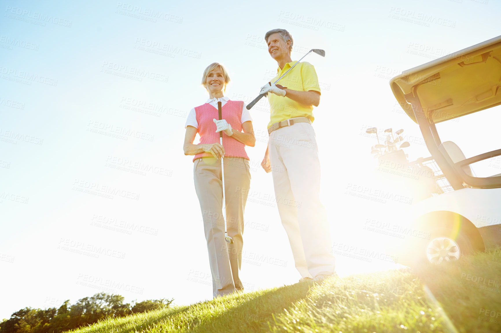 Buy stock photo Sports, morning and mature couple on golf course, field and grass for game, match and competition. Retirement, lens flare and man and woman for activity, hobby and practice for relaxing together