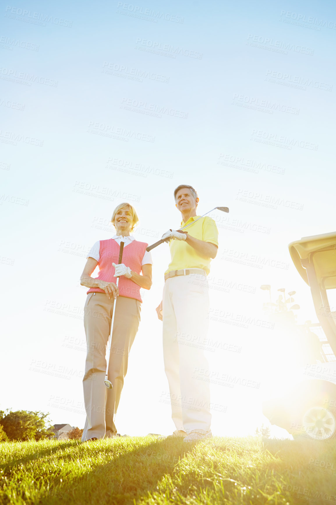 Buy stock photo Sports, sunshine and mature couple on golf course, field and grass for game or competition with flare in morning. Retirement, mockup space and low angle of man and woman for activity, fun and playing