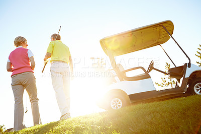 Buy stock photo Rear view shot of an elderly couple walking to their golf cart