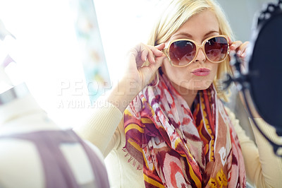Buy stock photo An attractive young woman trying on sunglasses in a department store