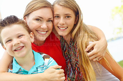 Buy stock photo Smiling mother embracing her teen daughter and young son while outdoors