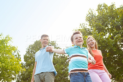 Buy stock photo Child, parents and holding hands in nature for game, swinging and playful on holiday. Kid, family and gesture in park for fun activity, energy and freedom on adventure with trust on summer vacation