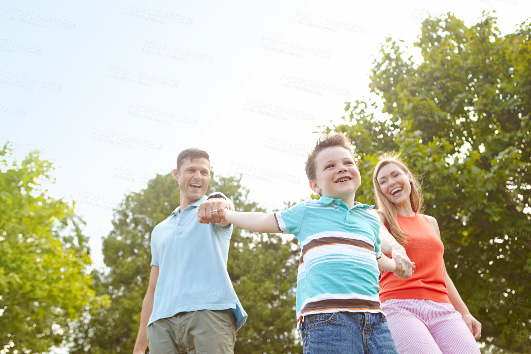 Buy stock photo Child, parents and holding hands in nature for game, swinging and playful on holiday. Kid, family and gesture in park for fun activity, energy and freedom on adventure with trust on summer vacation