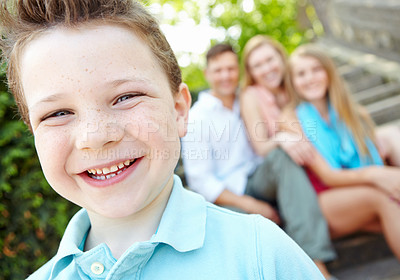 Buy stock photo Cute little boy with family sitting behind him while outdoors