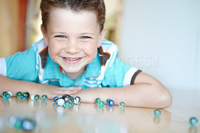 Buy stock photo Floor, boy and smile with playing marbles on portrait for fun on school break at home in Scotland. Male person, kid and happy at apartment with toys for games, child growth and brain development