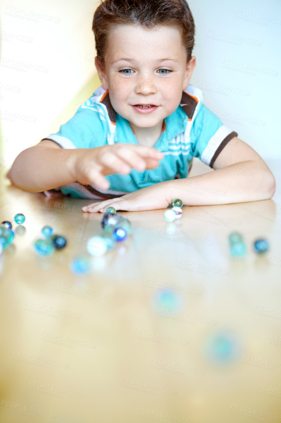 Buy stock photo Home, boy and happy with smile marbles for fun on school break on floor for activity. Male person, kid and concentration at apartment with toys for games, child growth and brain development or care